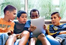 Four boys sitting on a beanbag staring at tablet screen